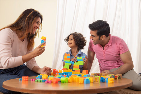 Parent and son playing together with toy blocks 