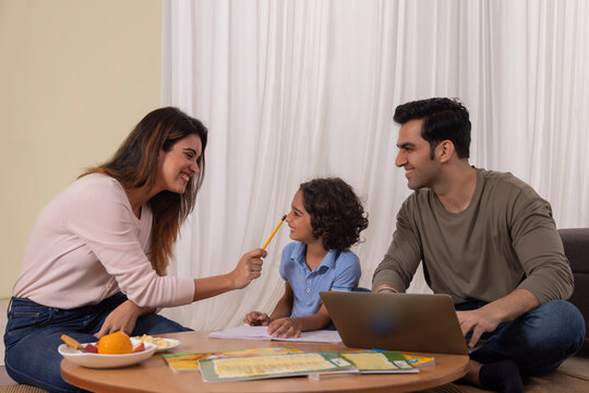 Mother kidding with her son and father using laptop