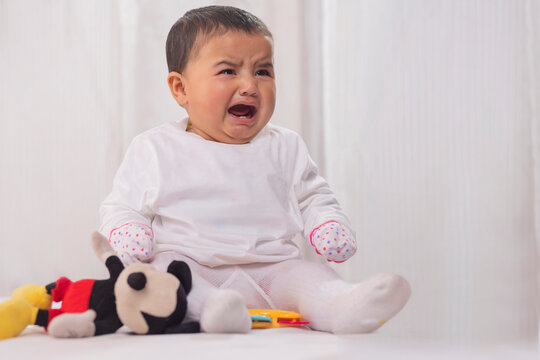 Little baby crying while sitting on bed