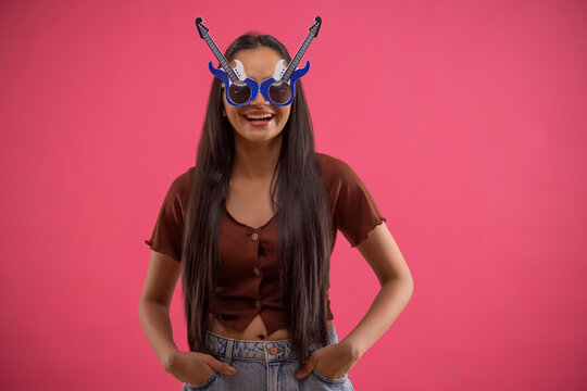 Portrait of a funny young woman wearing guitar shaped eye glasses