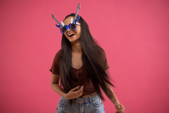 Portrait of a funny young woman wearing guitar shaped eye glasses