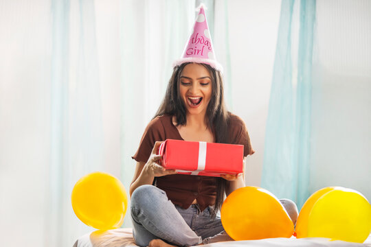 Portrait of excited young woman with birthday gift in her hand
