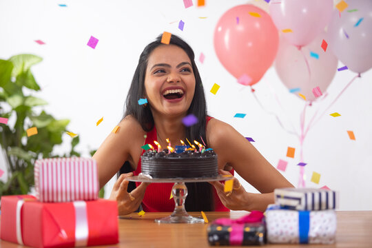 Cheerful young woman celebrating her birthday at home