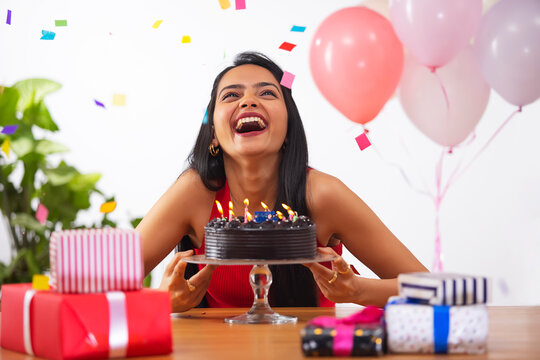 Cheerful young woman celebrating her birthday at home