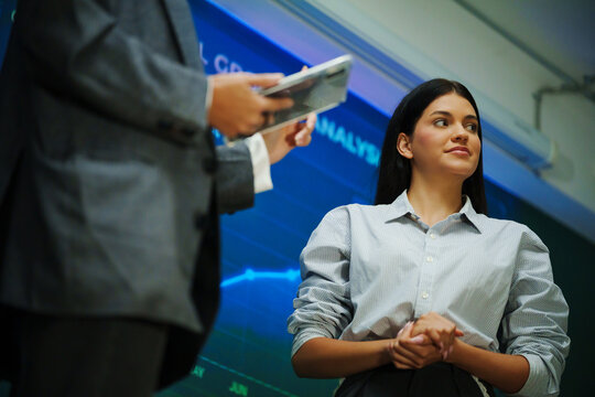 Professional businesswoman listening attentively during a financial market presentation and corporate seminar, with colleagues discussing investment analysis