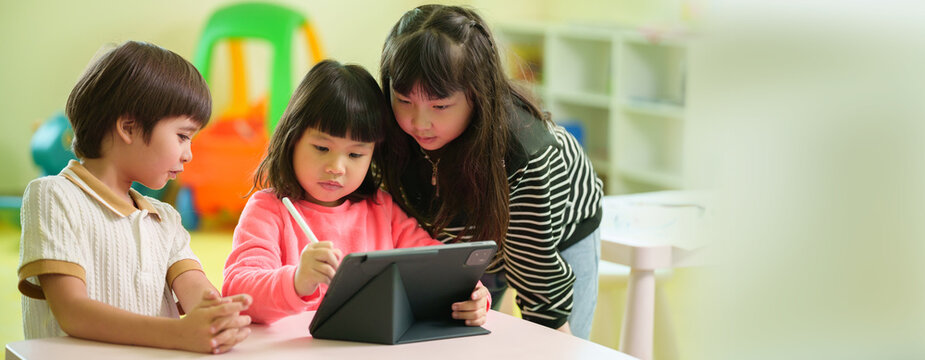 Children learning together with a digital tablet and stylus in a classroom, exploring creative educational activities through technology.