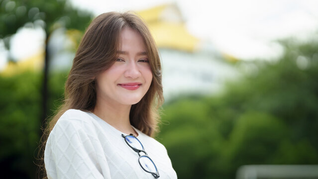 Smiling young woman posing outdoors in a bright natural setting, showing confidence and a positive lifestyle in a casual portrait suitable for education, university, youth and wellness themes.