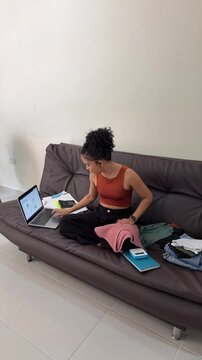 Young female entrepreneur managing online clothing store from home