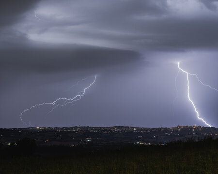 View of lightning strikes illuminating the night sky over the town of Corridonia, Marche, Italy.