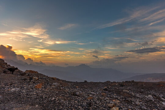 View of Jebel Jais mountains at sunset with a goat standing on the rocky terrain in Ras Al Khaimah, United Arab Emirates.