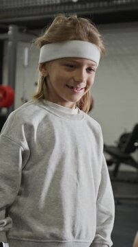 Vertical video of Caucasian child boy giving high five to anonymous trainer and chatting in gym. Footage is perfect for kids fitness apps and wearable technology promos