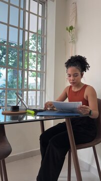 Young latina woman reviewing documents at home office
