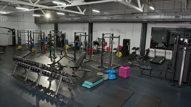 Empty modern gym interior displaying various fitness equipment from high angle view. Clip is ideal for fitness center advertisements, health club marketing, or sports business promotions