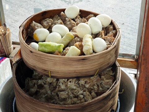 Steamed Indonesian siomay dim sum with boiled eggs, cabbage rolls, and tofu served in stacked wooden bamboo steamers