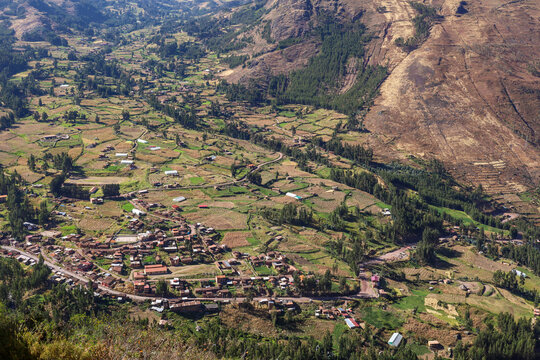 View of the historic town of Pisac nestled in the Sacred Valley with agricultural terraces and surrounding mountains in Pisac, Cusco, Peru.