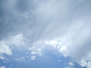 Obraz premium Blue sky filled with thick white and grey storm clouds captured during a bright summer afternoon looking upwards towards the high vast infinite atmospheric space
