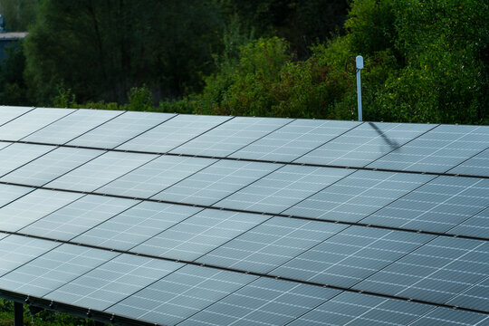 View of solar panels installed in an outdoor field with lush green trees in the background in Dabrowa Gornicza, Silesian Voivodeship, Poland.