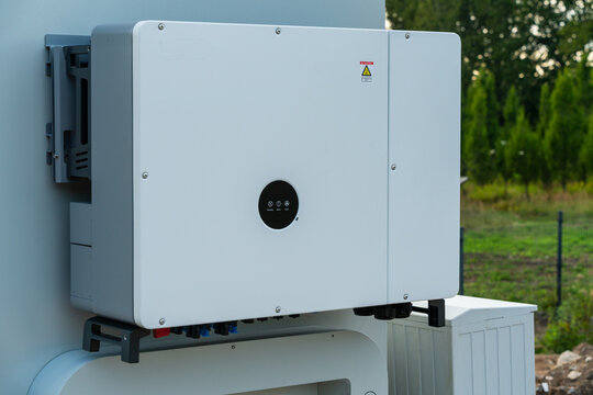 View of a modern solar inverter mounted on an outdoor wall with electrical connections and a circular display panel in Dabrowa Gornicza, Silesian Voivodeship, Poland.