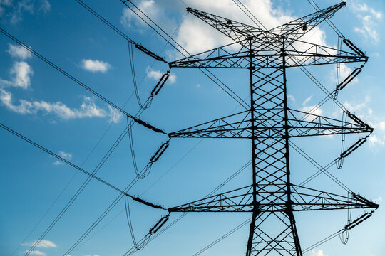 View of a high-voltage electricity pylon with power lines against a blue sky in Dabrowa Gornicza, Silesian Voivodeship, Poland.