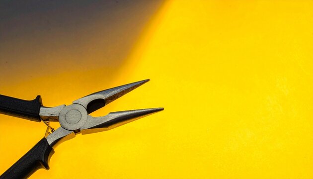 Needle nose pliers with black handles on black background.
