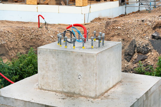 View of a concrete foundation block with protruding anchor bolts and electrical conduits at a construction site in Riga, Latvia.