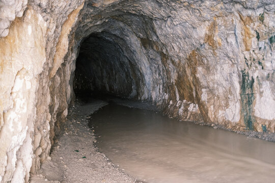 View of the historic stone tunnel carved into the mountain with a stream flowing through the passage in Kemaliye, Erzincan, Turkiye.