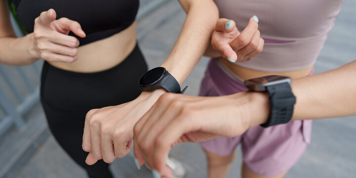 Cropped view of women checking smartwatches for fitness technology and tracking