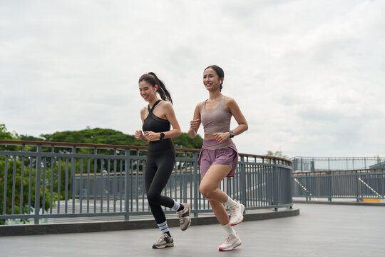 Asian women running together outdoors for healthy cardio fitness