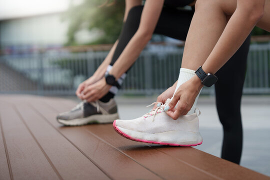 Close up of hands tying running shoes on bench for outdoor workout