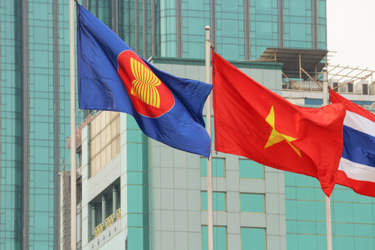 VUNG TAU, VIETNAM - FEBRUARY 5, 2026: The official ASEAN flag and the national flag of Vietnam waving on flagpoles against a modern office building.