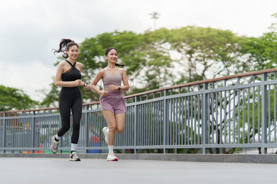 Asian women running outdoors on bridge for fitness and active lifestyle