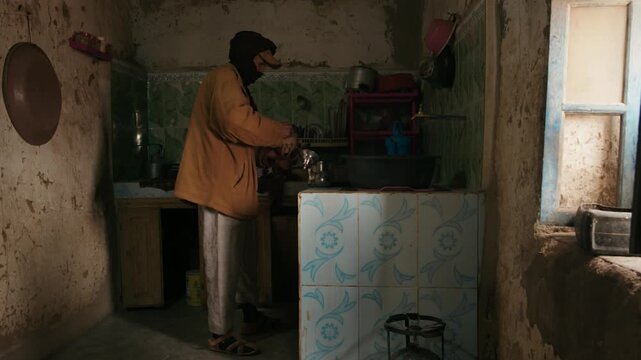 Middle Eastern man making traditional hot tea in an old, weathered kitchen of a rural house