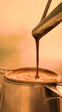 Malaysian kopi pours from a long spouted kettle into a mu