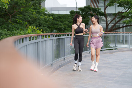 Two Asian women walking and chatting after workout for healthy active lifestyle