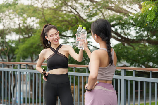 Asian women toasting water bottles outdoors for hydration and wellness