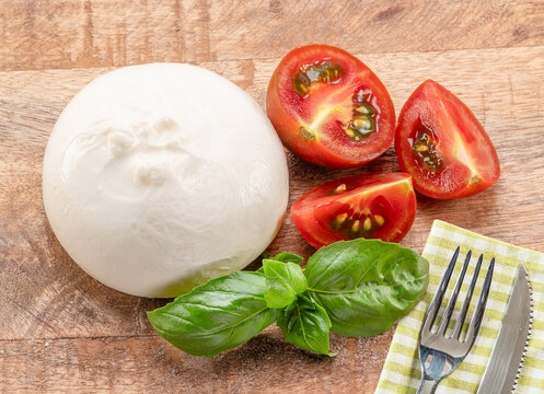 Fresh burrata cheese (or buffalo mozzarella) with sliced cherry tomatoes and basil