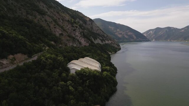 Aerial drone footage of the modern glass protective structure and visitor center at Lepenski Vir archaeological site in Iron Gate National Park, Serbia. 20.07.2026