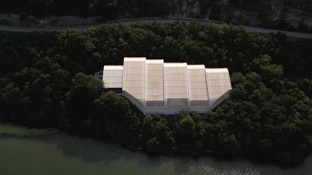 Aerial drone footage of the modern glass protective structure and visitor center at Lepenski Vir archaeological site in Iron Gate National Park, Serbia. 20.07.2026