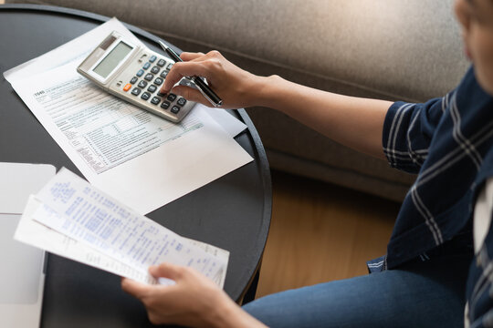 Close up of woman hands holding receipt and using calculator for financial budget and tax return planning.