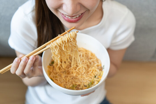 Close-up people eating instant noodles at home.