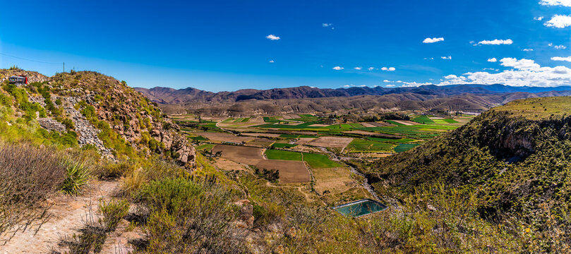 A view of the landscape showing the rugged terrain and green agricultural fields of the Colca Canyon region in the Andes mountains of Peru in the dry season