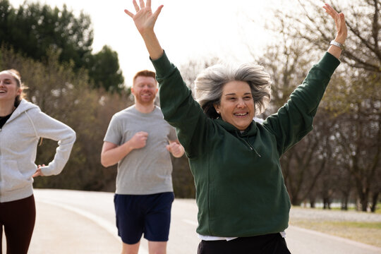 Smiling older woman celebrating success during a run with a diverse group