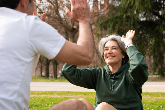 Happy senior woman high fiving a man, celebrating achievement during an outdoor fitness session