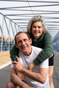Happy mature couple embracing on a modern pedestrian bridge, enjoying time together