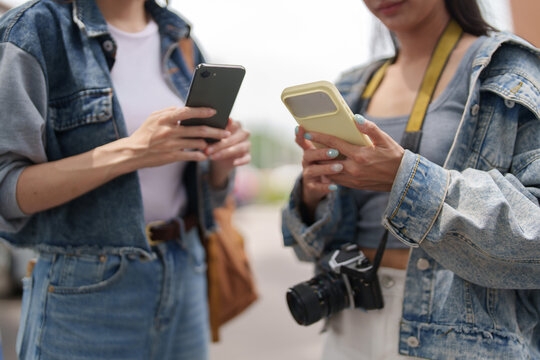 Two female tourists using smartphones outdoors for travel navigation and tourism