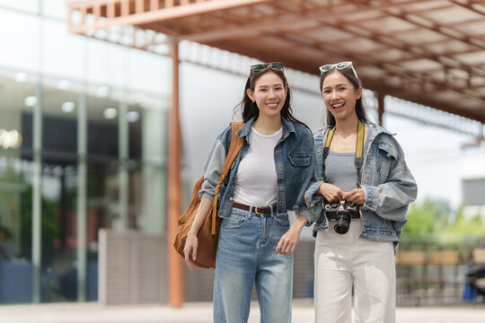 Happy Asian female tourists walking together with camera for city travel vacation