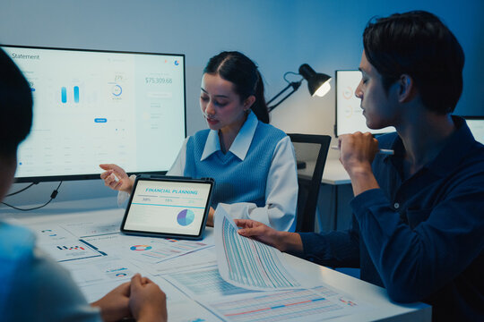 Asia businesspeople presentation sales meeting plan analysis statistics brainstorm and tablet point graph chart take note in office conference room at night. Business finance partner strategy success.