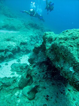 View of scuba divers exploring ancient underwater ruins with submerged amphorae on the seabed in Kas, Antalya, Turkey.