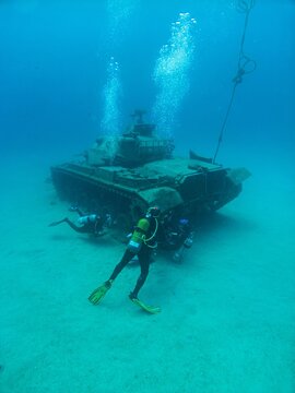 View of scuba divers exploring an underwater tank on the sandy seabed in Kas, Antalya, Turkey.