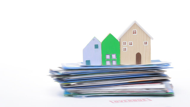 Residential property model on bill stack depicts financial stress debt crisis during real estate market inflation period